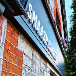Smaash Burger restaurant sign on brick wall